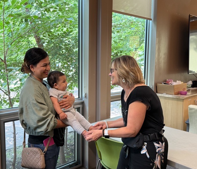 A mother holding her baby and a member playing with the baby