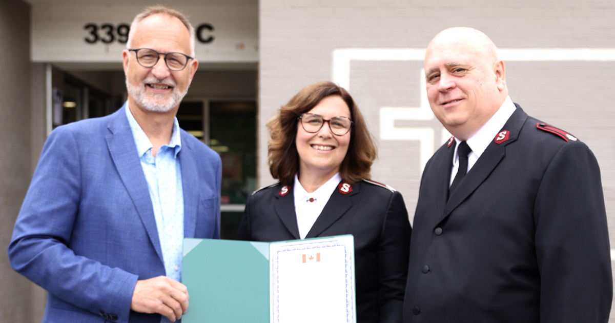 Three people smiling, holding a folder