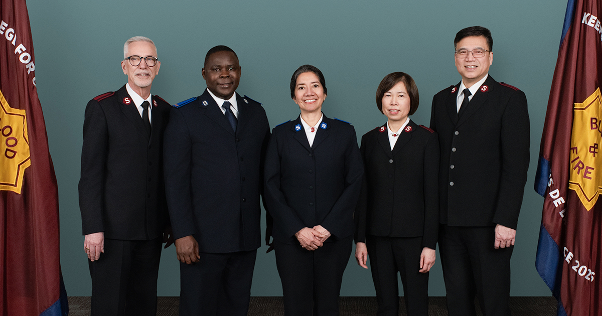 Five people standing next to flags
